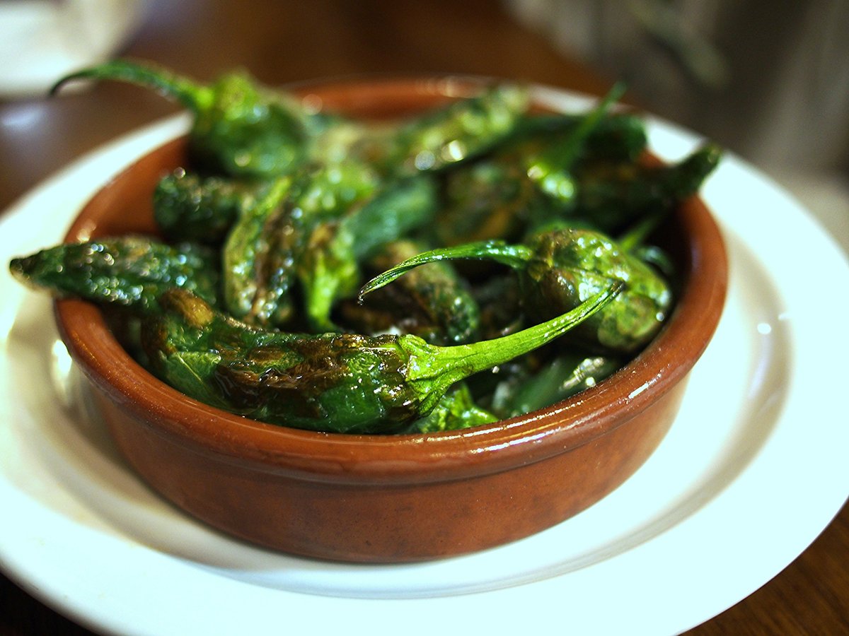 Cazuela de barro con pimientos fritos, servida como tapa.